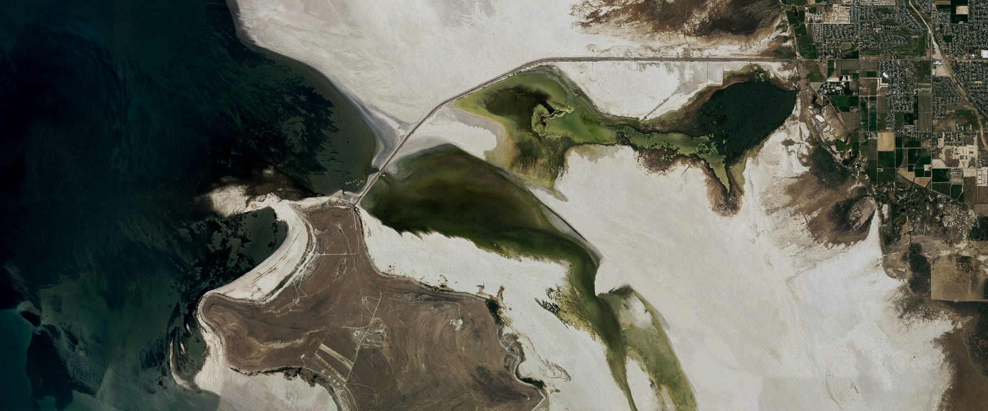 Aerial photo of the north end of Antelope Island on Great Salt Lake, with the causeway across pale salt flats and open water to the west